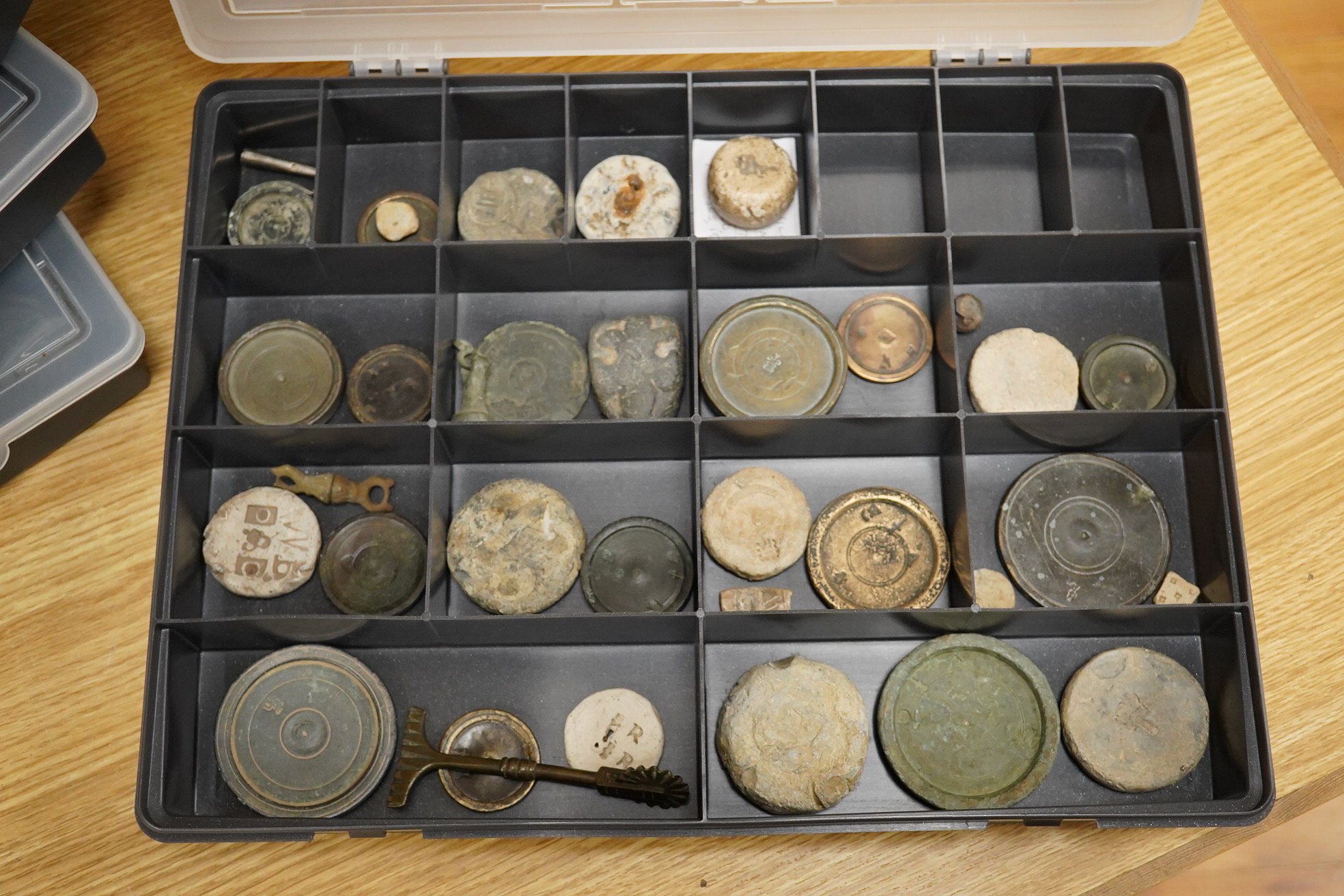 A collection of 16th century to 19th century bronze and lead circular trade weights, stamped with Royal Cyphers, weights, proof marks, the assay dagger for London, etc., contained within four plastic collector’s trays